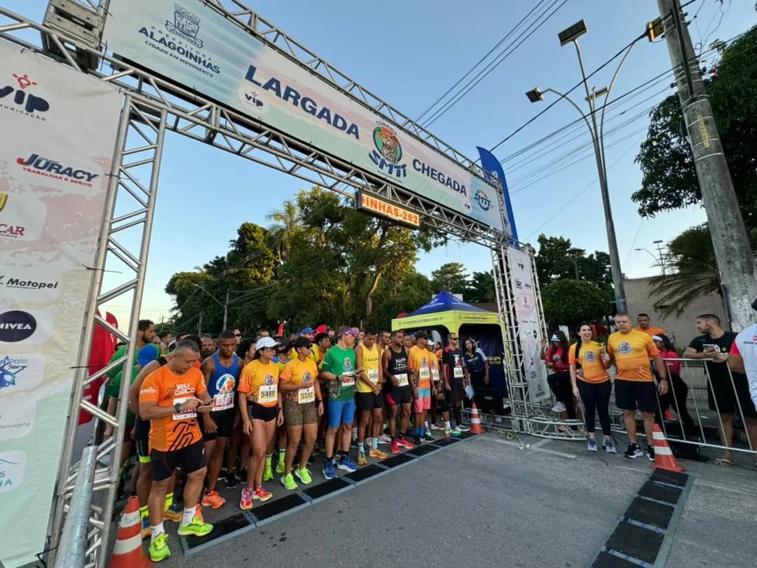 Corredores na pista de largada, a maioria com camisas na cor laranja