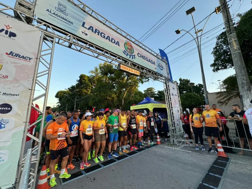 Corredores na pista de largada, a maioria com camisas na cor laranja